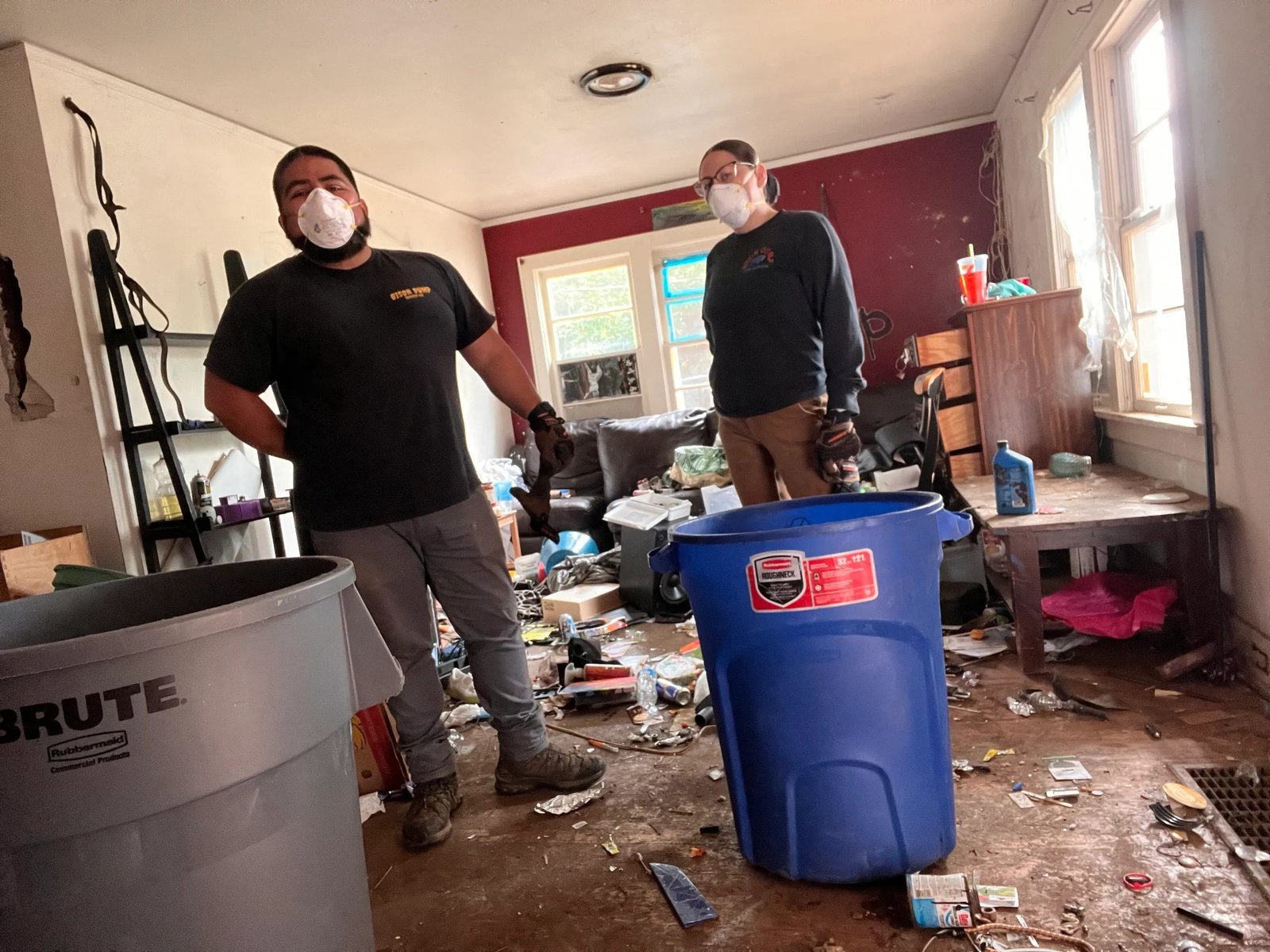 Masked Bison Dump crew member clearing a cluttered room during a Salem hoarder cleanout